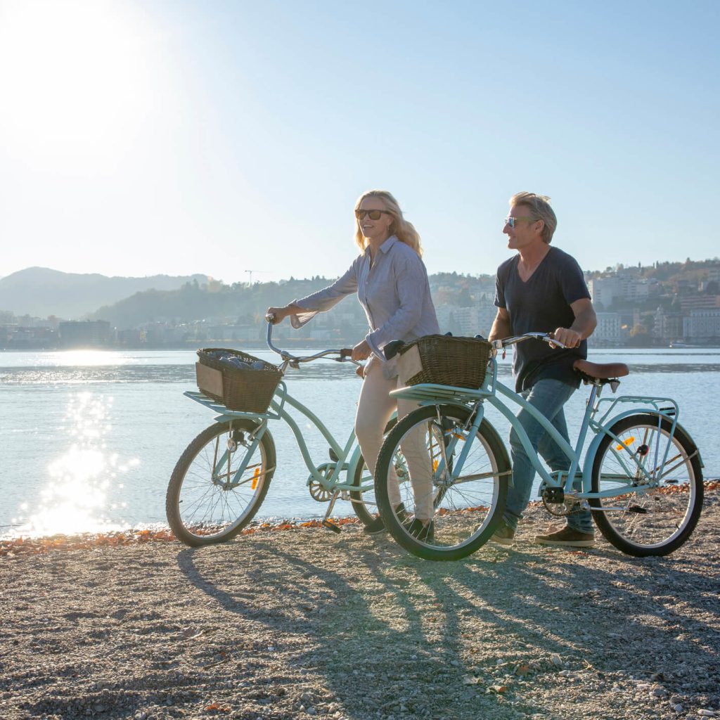 Couple walking bikes on the beach